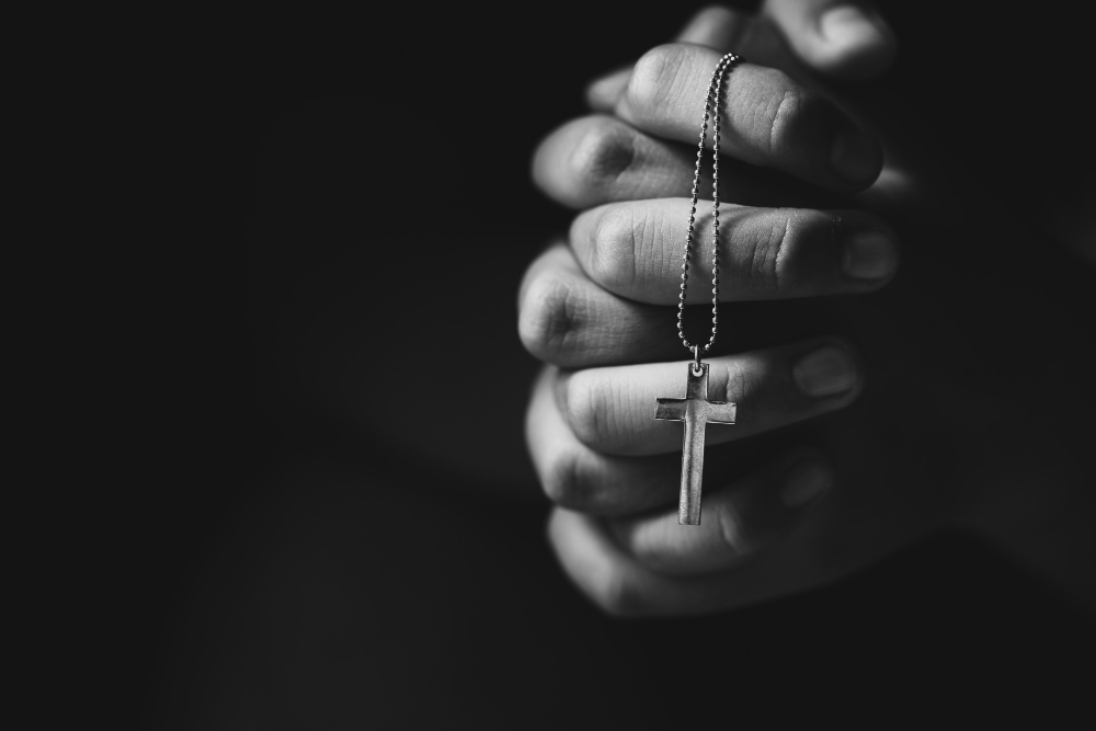 hands holding cross while praying