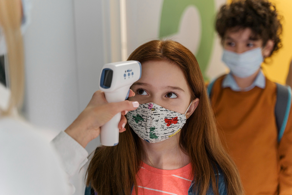 teacher with medical mask checking children s temperature school