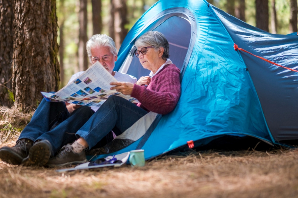 adult mature retired couple enjouying wild camping outdoor forest looking together paper map choose adventure destination see live travel tourism concept